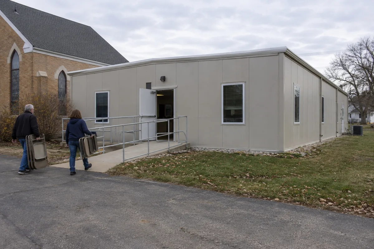 Volunteers moving chairs beside a modular church annex