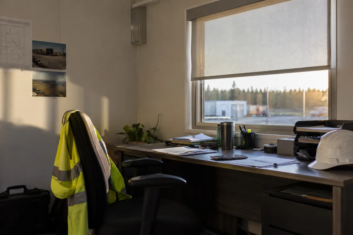 Modular office desk beside a window and roller shade